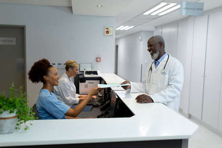Diverse male doctors and female nurse passing medical documentation over the counter at hospital. medicine, health and healthcare services.の写真素材
