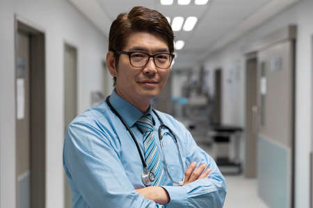 Portrait of mixed race male doctor standing in hospital corridor. medicine, health and healthcare services.の写真素材
