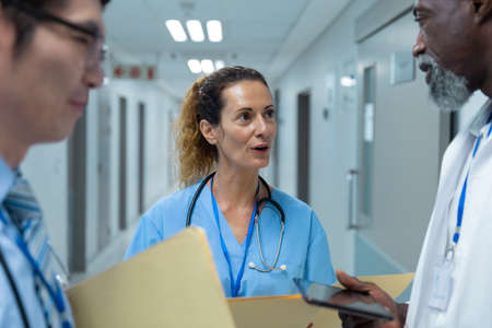 Diverse group of male and female doctors standing discussing on corridor. medicine, health and...