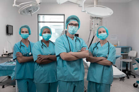 Diverse group of male and female doctors standing in operating theatre wearing face masks. medicine, health and healthcare services during coronavirus covid 19 pandemic.の写真素材
