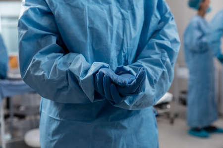 Midsection of doctor wearing surgical overalls and gloves. medicine, health and healthcare services during coronavirus covid 19 pandemic.の写真素材