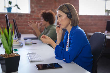 Asian businesswoman sitting in front of computer wearing headset having video call. independent...