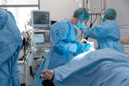 Caucasian female surgeon wearing face mask putting oxygen mask on patient lying in bed. medicine,...