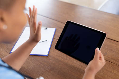African american female doctor giving video call consultation using tablet, copy space on screen. telemedicine online healthcare during quarantine lockdown.の写真素材