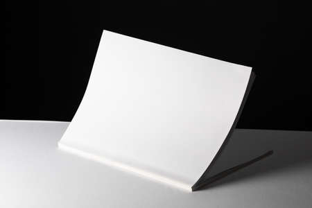 Composition of half opened book with blank pages on black and white background. reading, writing and...