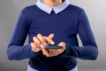 Mid section of african american businesswoman using smartphone against grey background. business,...