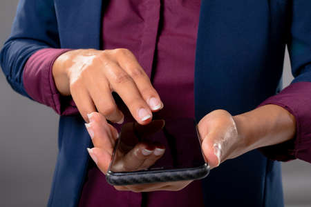 Mid section of businesswoman using a smartphone against grey background. business, professionalism...