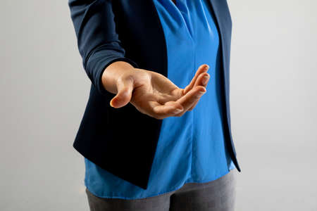 Mid section of businesswoman holding a invisible object against grey background. business,...