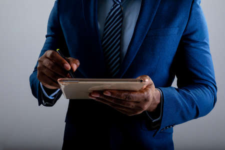 Mid section of businessman using graphic tablet against grey background. business, professionalism and technology conceptの写真素材