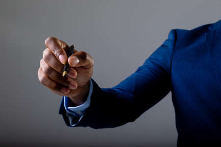 Mid section of businessman writing on invisible screen against grey background. business,...