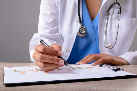 Mid section of female doctor writing on clipboard against grey background. healthcare and medical...