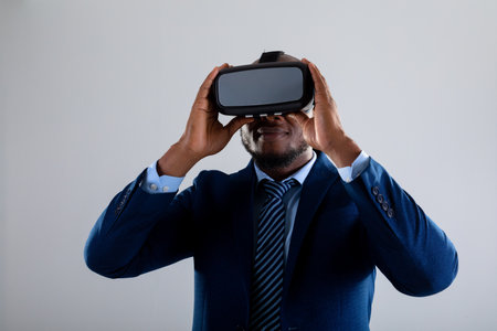 African american businessman wearing vr headset smiling against grey background. business, professionalism and technology conceptの写真素材