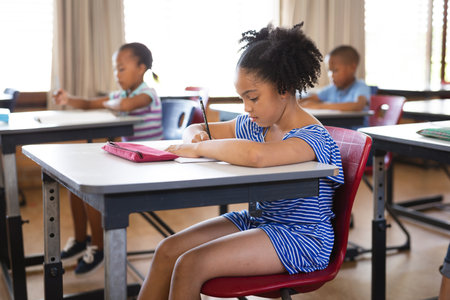 African american girl studying while sitting on her desk in the class at school. school and...