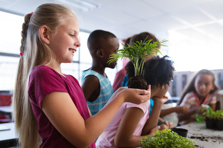 Caucasian girl smiling while holding a plant seedling in the class at school. school and education conceptの写真素材