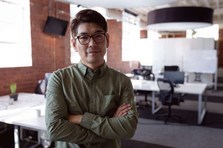 Portrait of serious asian businessman standing in office with arms crossed looking to camera. working in business at a modern office.の写真素材