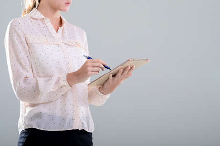 Caucasian businesswoman using graphic tablet, isolated on grey background. business, technology, communication and growth concept.の写真素材