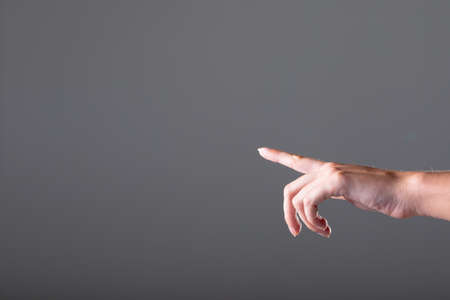 Close up of caucasian businesswoman pointing with her finger, isolated on grey background. business, technology, communication and growth concept.の写真素材
