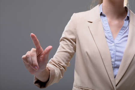 Midsection of caucasian businesswoman touching virtual interface on grey background. business, technology, communication and growth concept.の写真素材