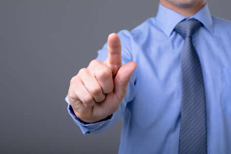 Midsection of caucasian businessman touching virtual interface, isolated on grey background. business technology, communication and growth concept.の写真素材