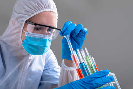 Caucasian female doctor wearing ppe suit holding test-tubes. medical and healthcare technology...