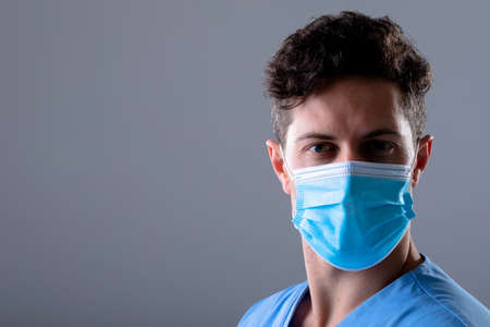 Caucasian male doctor wearing face mask, isolated on grey background. medical and healthcare technology concept during   pandemic concept digitally generated composite image.の写真素材