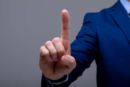 Midsection of caucasian businessman touching virtual interface, isolated on grey background....