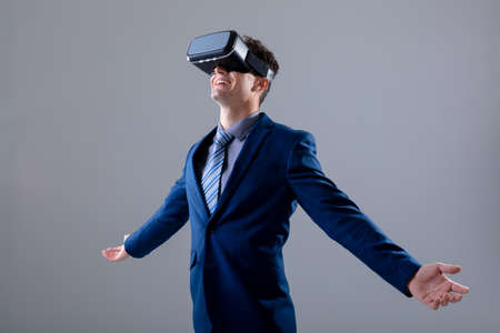 Caucasian businessman wearing vr headset widening his arms, isolated on grey background. business...