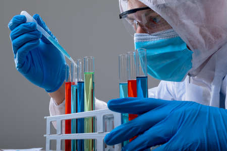 Caucasian male doctor wearing ppe suit holding test-tubes. medical and healthcare technology concept during   pandemic concept digitally generated composite image.の写真素材