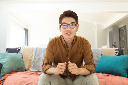 Asian man smiling during video call at home. domestic lifestyle and working online during  pandemic...