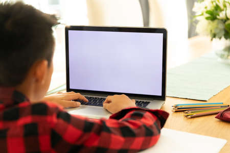 Asian boy using laptop with blank screen at home. domestic lifestyle and online education during ...