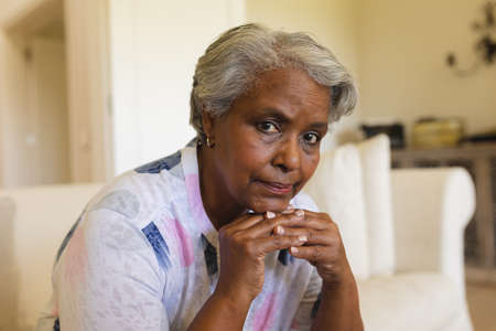 Portrait of senior african american woman sitting on sofa looking at camera. retreat, retirement and senior lifestyle concept.の写真素材
