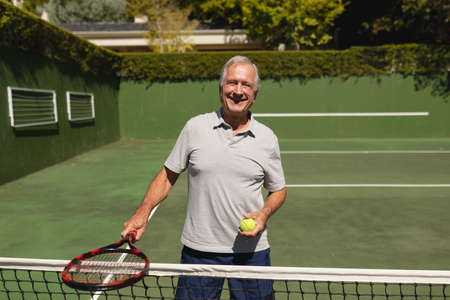 Portrait of senior caucasian man playing tennis on court holding tennis racket. retirement retreat and active senior lifestyle concept.の写真素材