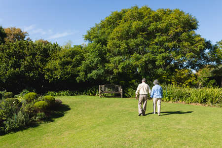 Senior caucasian couple walking together in sunny garden. retreat, retirement and happy senior lifestyle concept.の写真素材