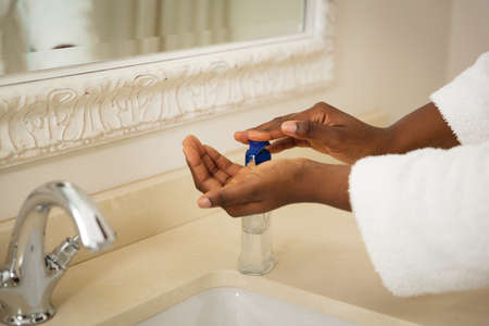 Midsection of african american woman in bathroom wearing bathrobe washing hands in basin. health,...