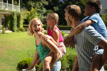 Happy caucasian couple with daughter and son outdoors, playing in sunny garden. family enjoying...