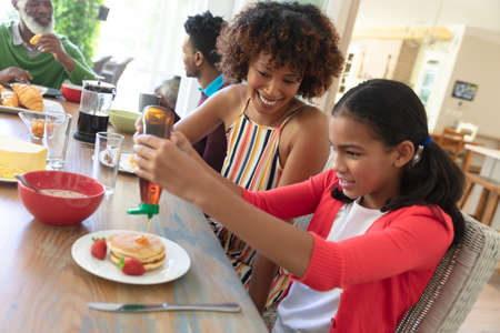 Happy african american family sitting at table smiling during breakfast. family enjoying quality free time together.の写真素材