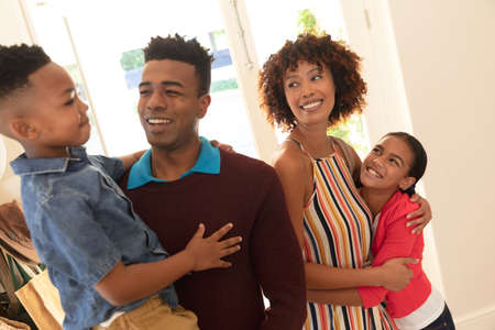 Happy african american couple with son and daughter embracing and smiling at home. family enjoying...