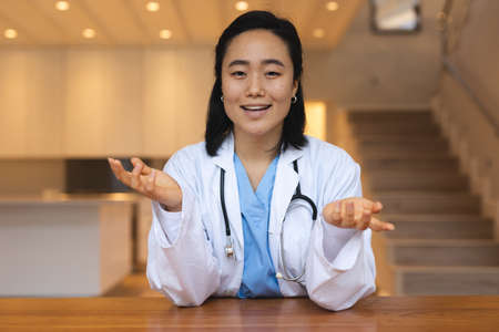 Portrait of asian female doctor sitting at desk talking during video consultation. telemedicine, online medical and healthcare service.の写真素材