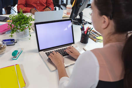 Caucasian female creative worker sitting at desk using laptop. modern office of a creative design...