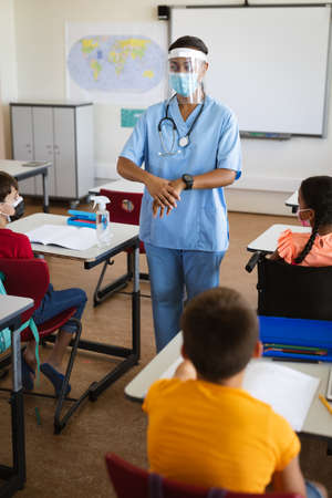 Female health worker showing students to use hands sanitizer in class at elementary school....