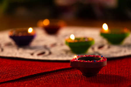 Four lit candles in small decorative clay pots burning on wooden table top. celebration, religion,...