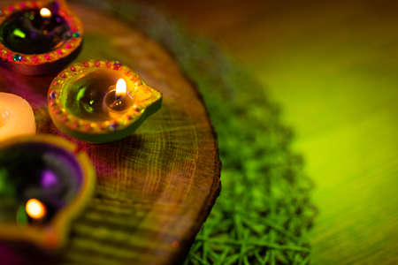 Lit candles in small decorative clay pots and tea light candle burning on round wooden board. celebration, religion, tradition and ceremony concept.の写真素材