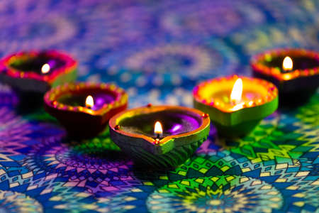 Lit candles in small decorative clay pots burning on patterned table cloth. celebration, religion,...