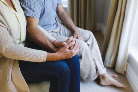 Senior caucasian couple sitting on sofa and holding hands. retirement lifestyle, spending time at home.の写真素材