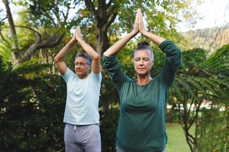 Happy senior caucasian couple practicing yoga, meditating in sunny garden. healthy retirement lifestyle, spending time at home.の写真素材