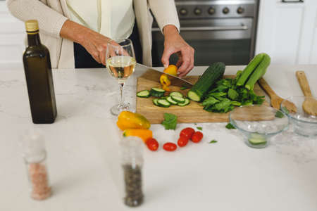 Midsection of senior caucasian woman in modern kitchen, chopping vegetables. retirement lifestyle, spending time at home.の写真素材