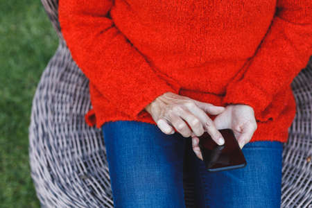 Mid section of senior caucasian woman using smartphone in garden. retirement lifestyle, spending...