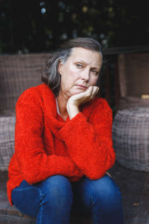 Thoughtful senior caucasian woman sitting and looking away in garden. retirement lifestyle, spending...