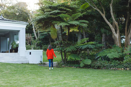 Senior caucasian woman walking towards house in her garden. retirement lifestyle, spending time...
