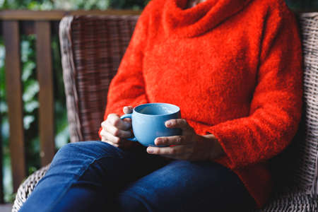 Midsection of senior caucasian woman sitting on chair, holding cup in garden. retirement lifestyle, spending time alone at home.の写真素材